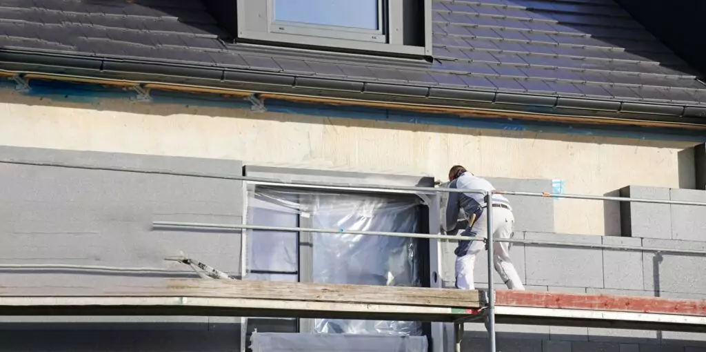 Ein Handwerker bringt ein Wärmedämmverbundsystem (WDVS) an einer Hauswand an.