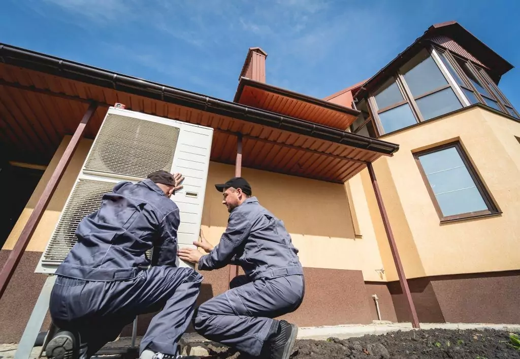 Handwerker installieren eine Wärmepumpe vor einem Haus