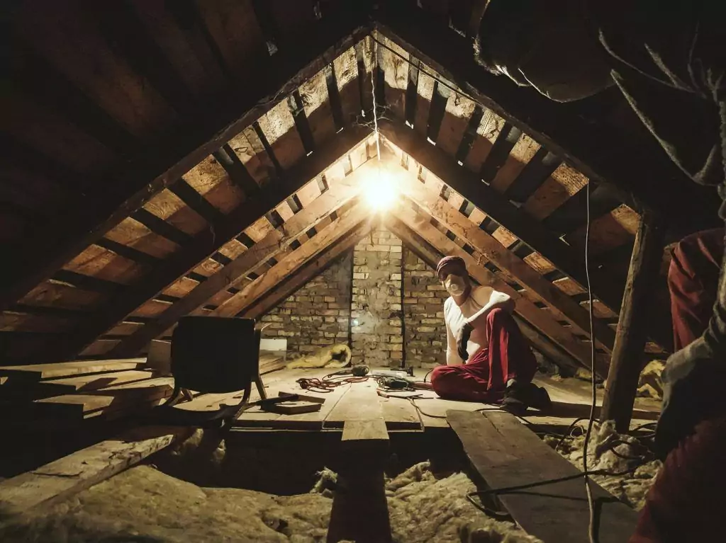 Mann führt Geschossdeckendämmung in altem Dachboden aus
