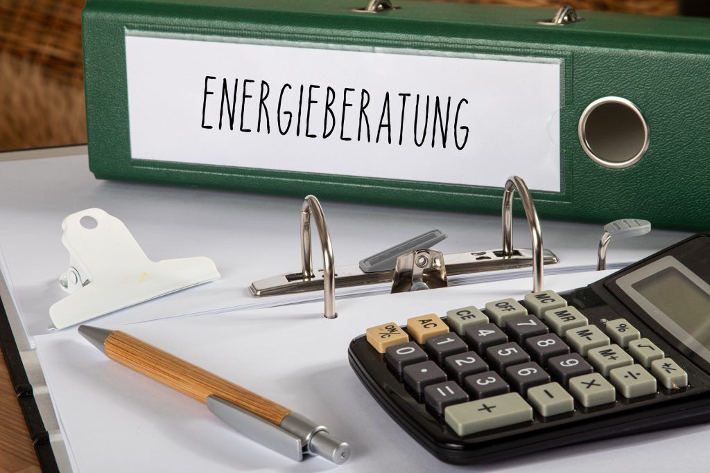 Ordner mit der Aufschrift "Energieberatung" zusammen mit Taschenrechner und Stift auf einem Schreibtisch