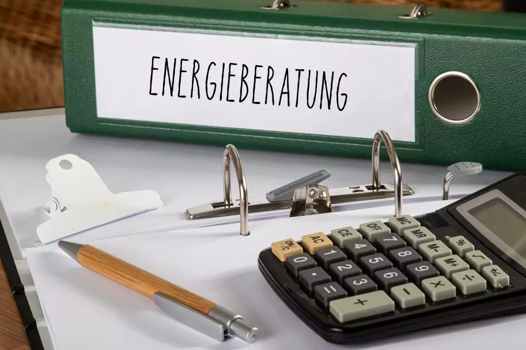Ordner mit der Aufschrift "Energieberatung" zusammen mit Taschenrechner und Stift auf einem Schreibtisch